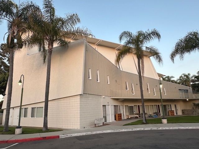 A large white building with palm trees in front of it