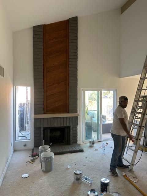 A man is painting a fireplace in a living room.