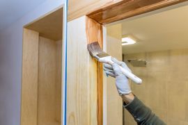 A person is painting a door frame with a brush.