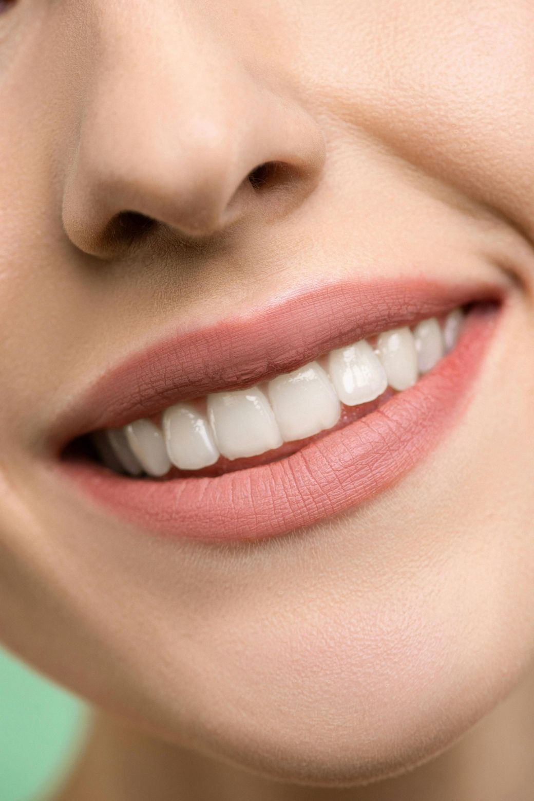 A close up of a woman 's smile with white teeth and pink lipstick.