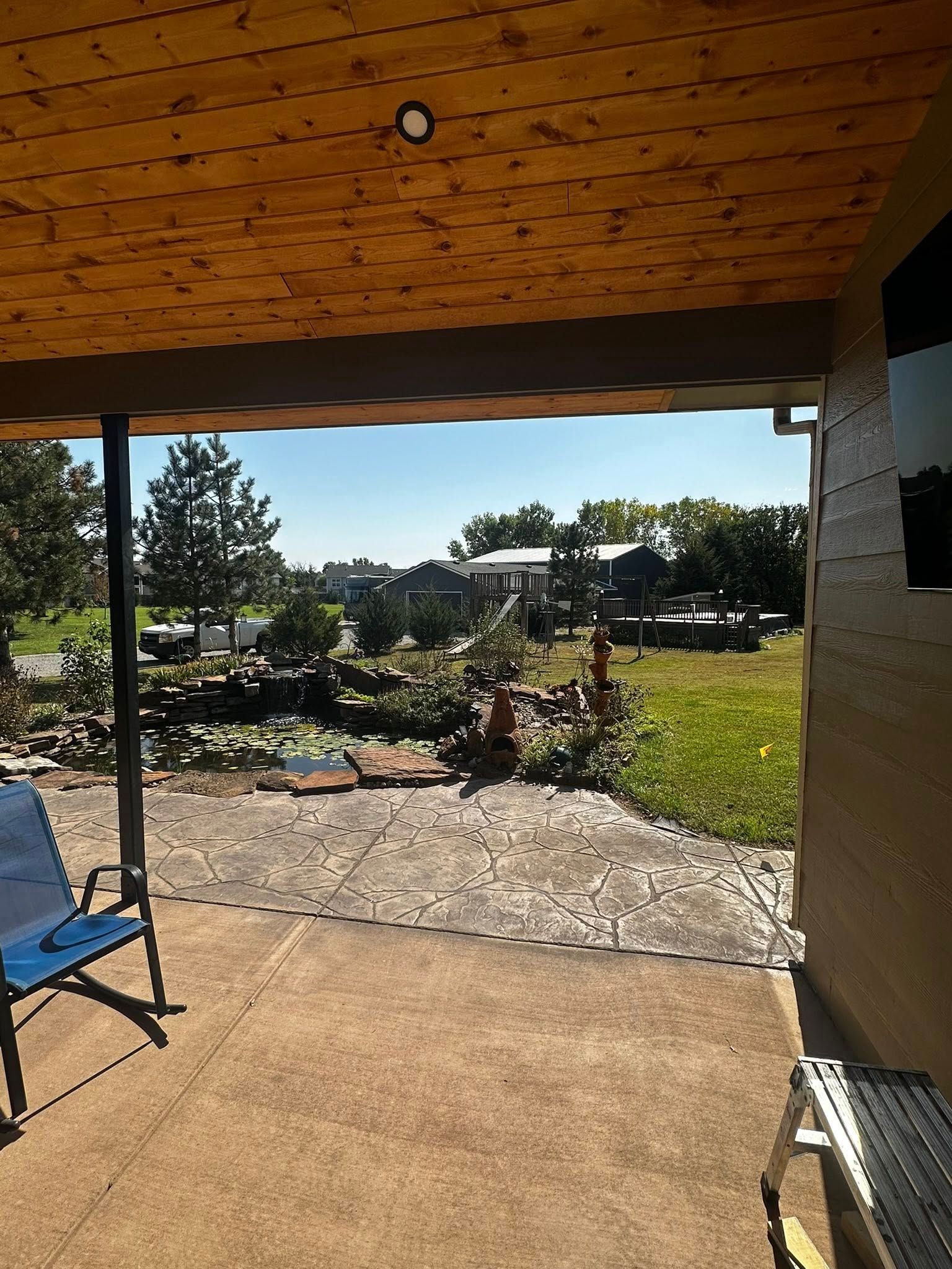 A patio with a chair and a grill and a view of a field.