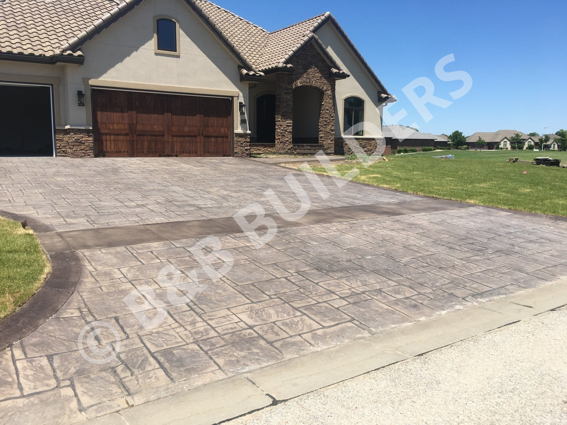 A concrete driveway stamped and colored to look like grey fieldstone with a darker grey border