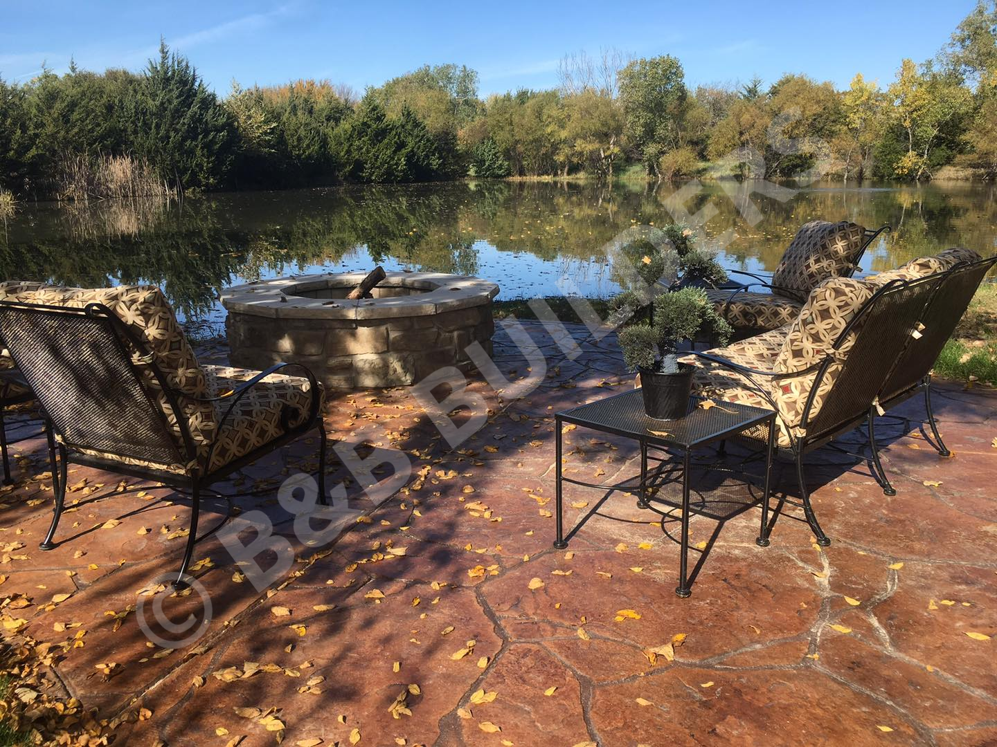 Lakeside seating area with masonry firepit and stamped concrete patio