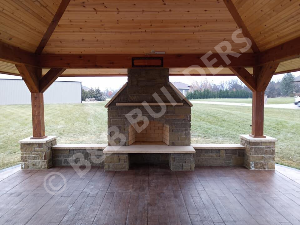 A large covered outdoor patio with large stone fireplace