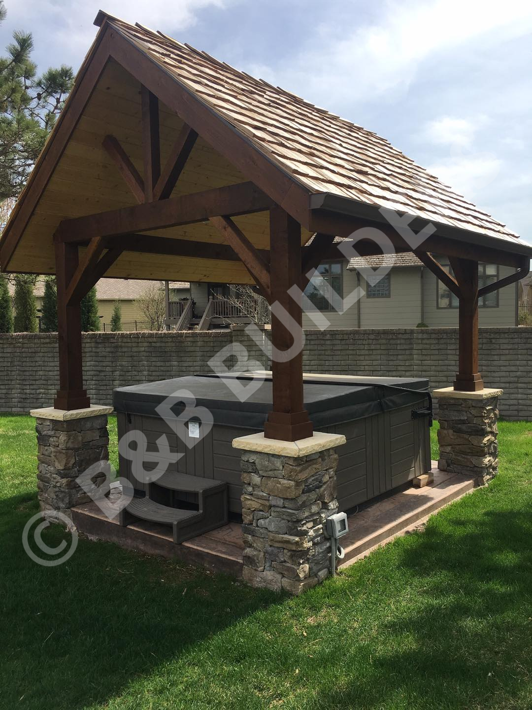Hot tub area with concrete deck, stone and timber roof