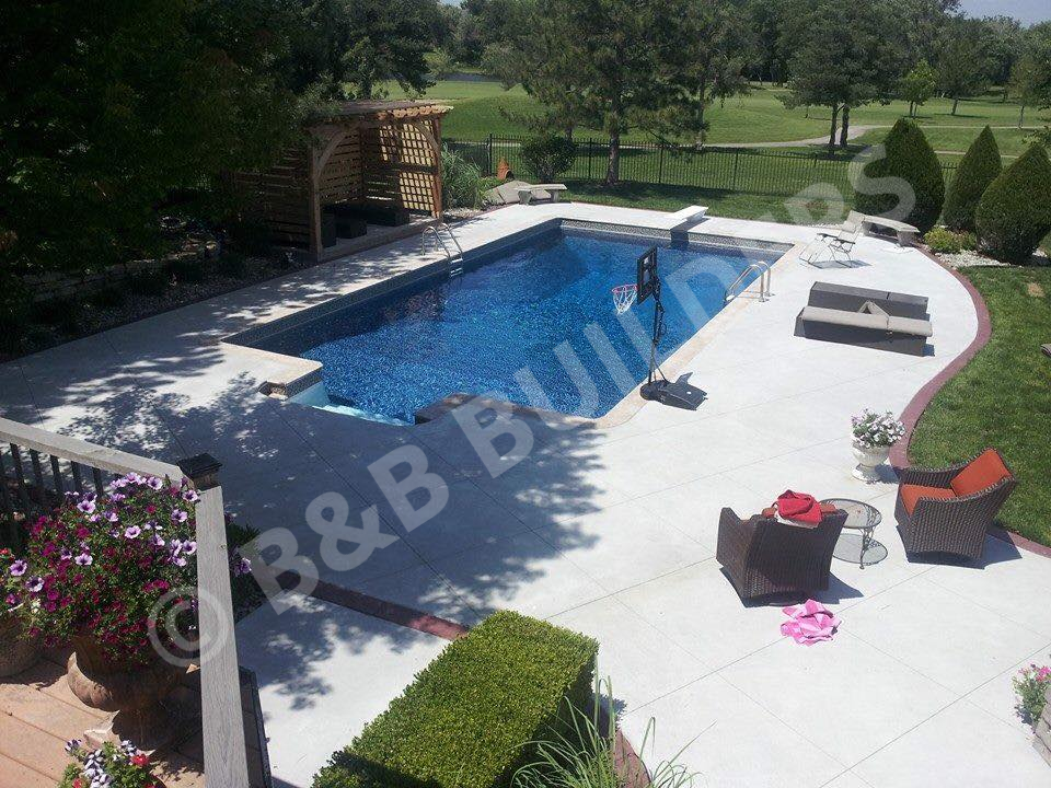 Rectangular pool with concrete pool deck, seating area, and poolside cabana