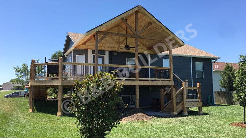 A beautiful two-level timber framed deck on the back of a green house.