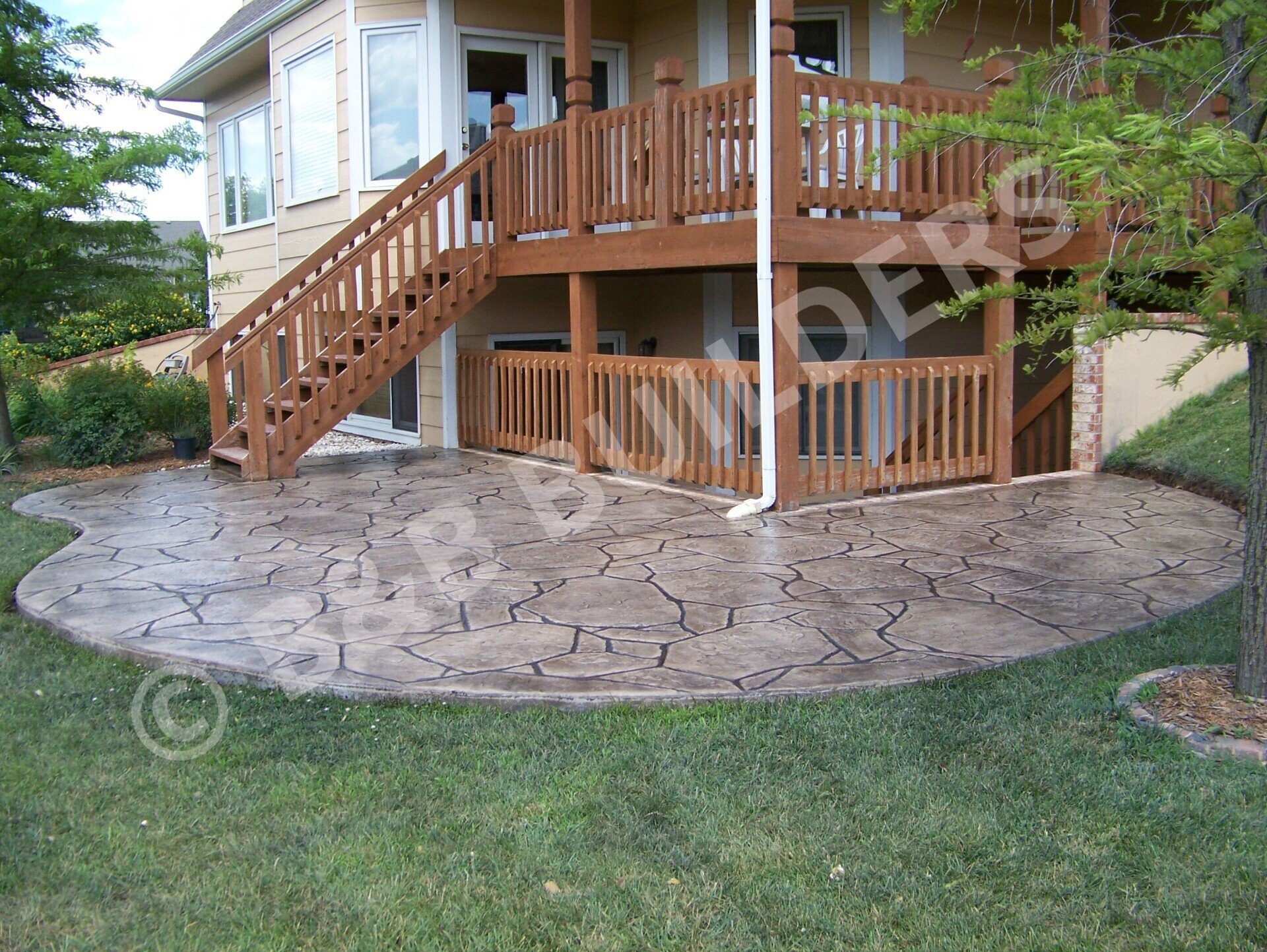 Two story wooden deck with stamped concrete patio