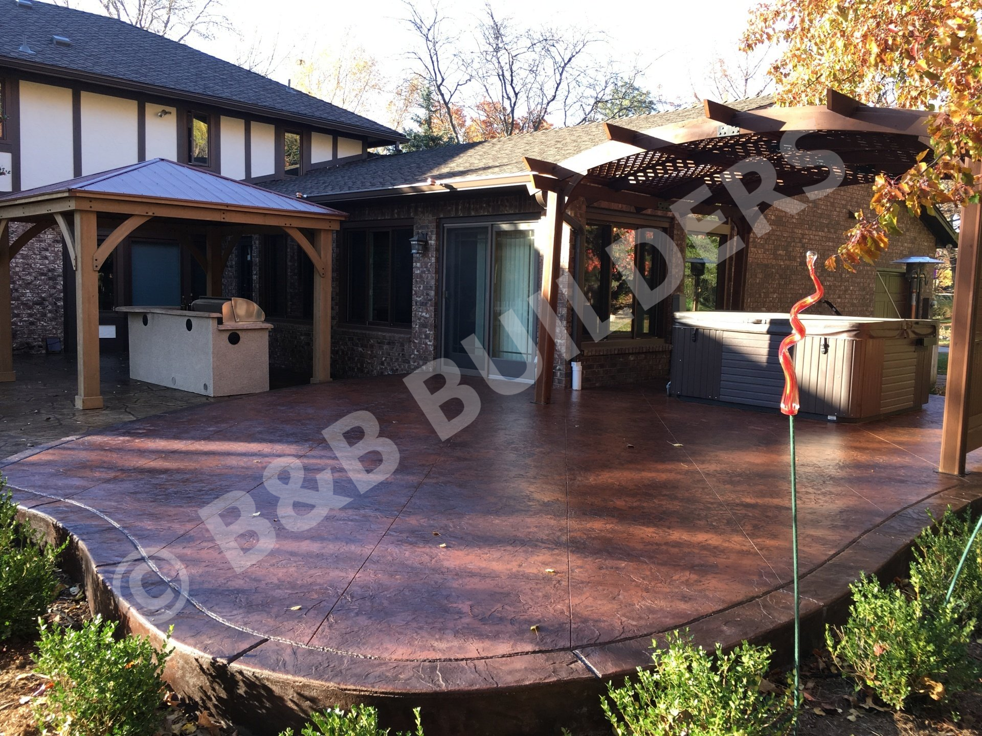 Stamped concrete patio with covered outdoor kitchen and pergola