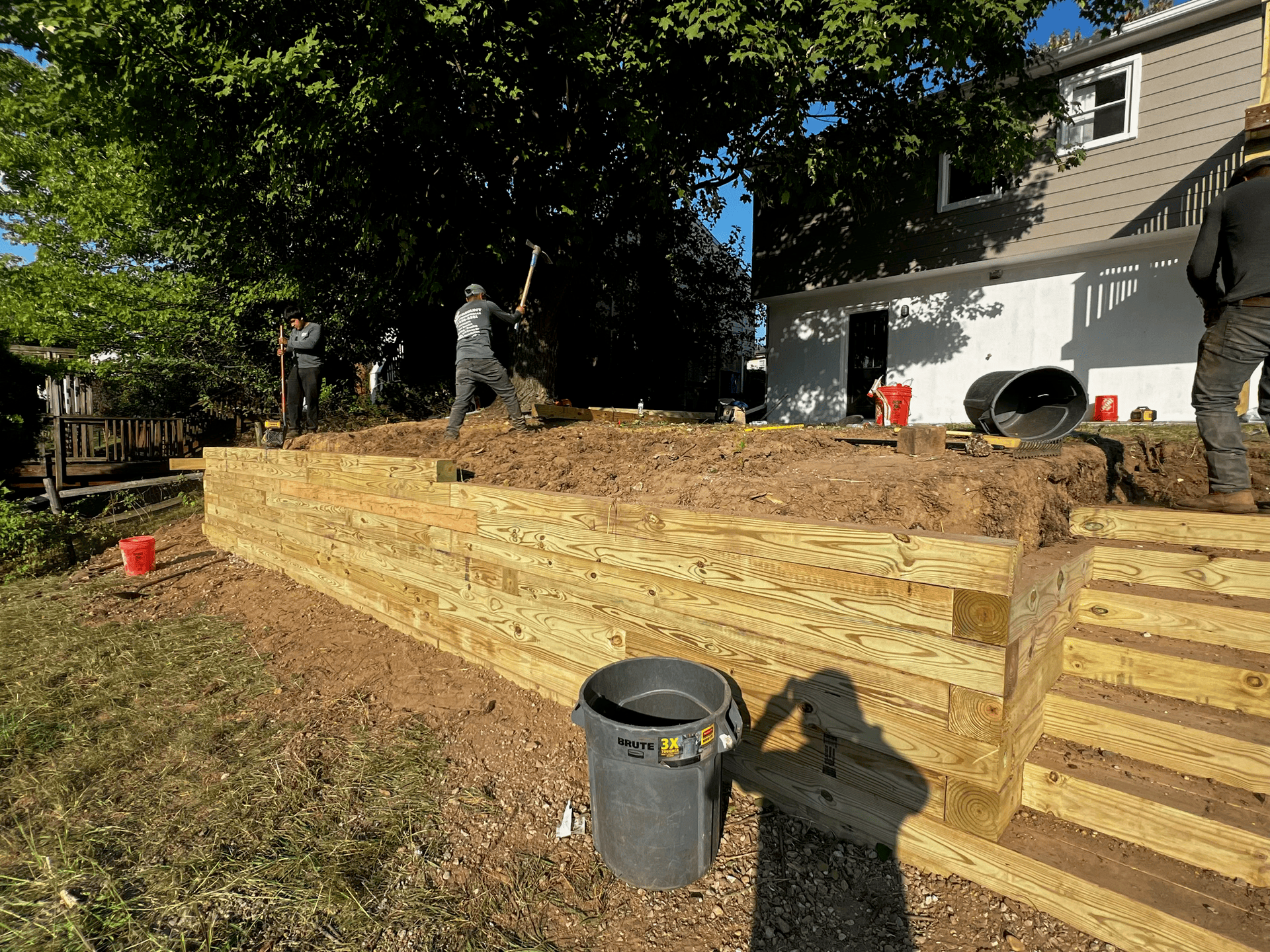 A group of people are working on a wooden deck in front of a house.