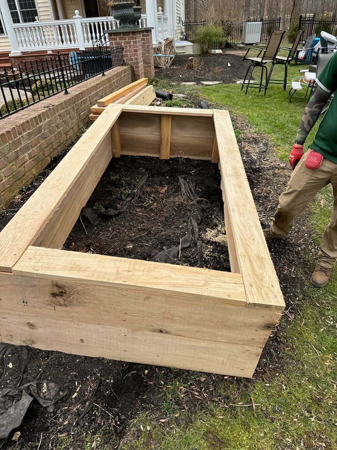 A man is standing next to a wooden box in a yard.
