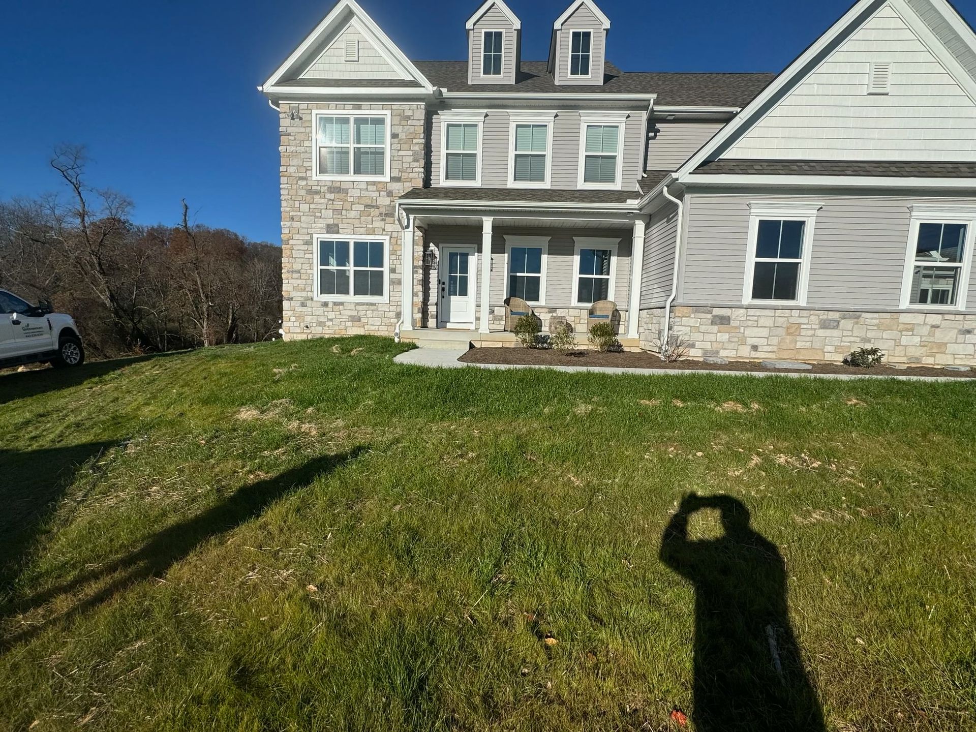 A white truck is parked in front of a large house