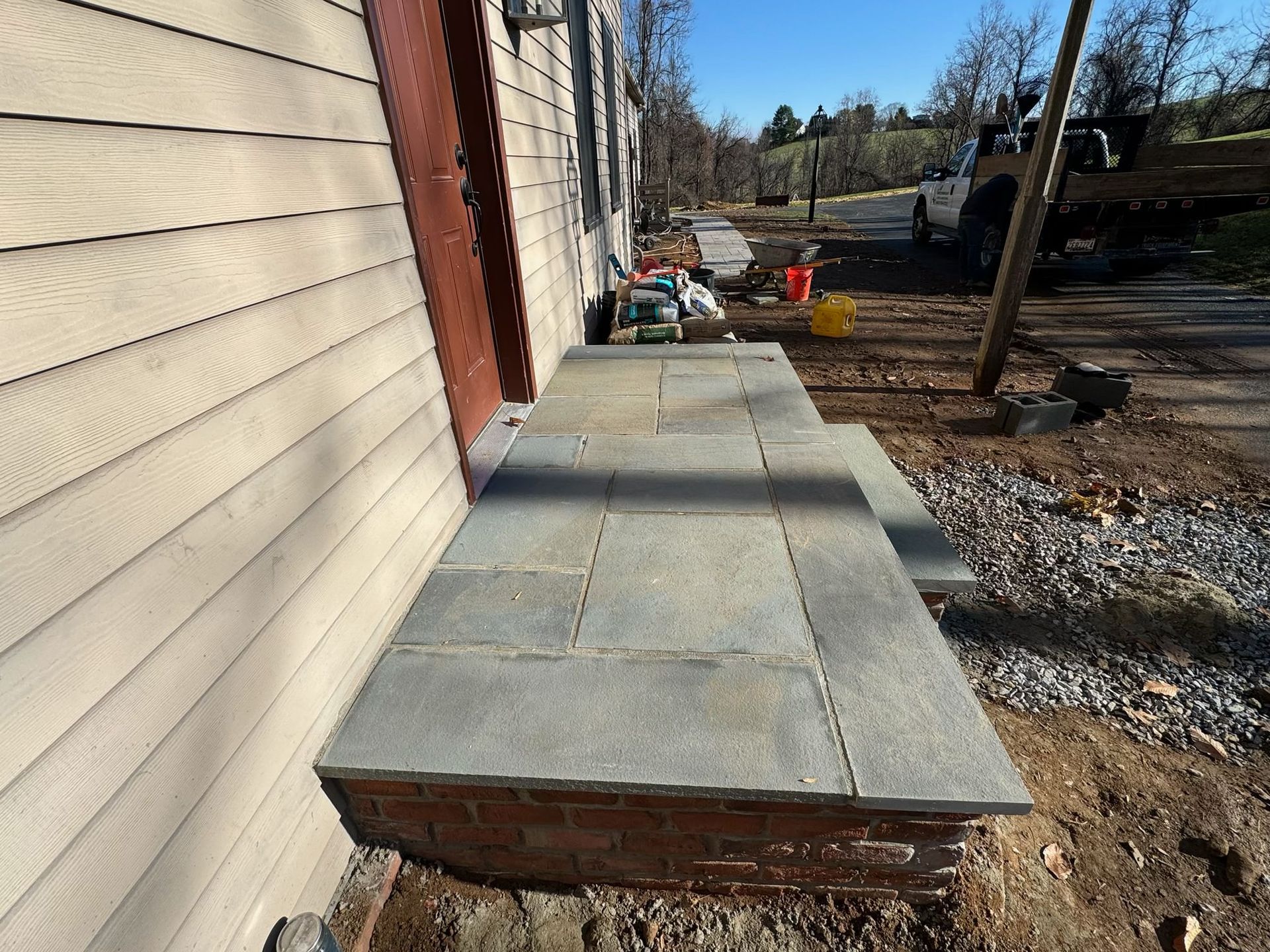 A stone walkway is being built on the side of a house