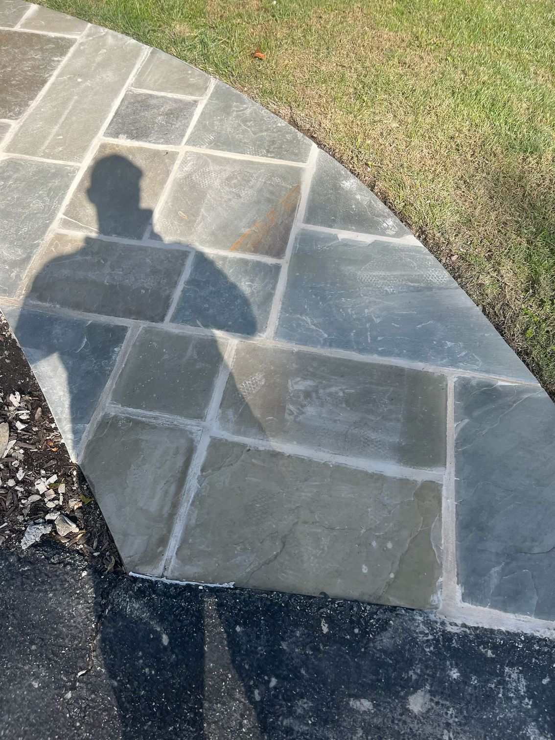 A shadow of a person is cast on a stone walkway.