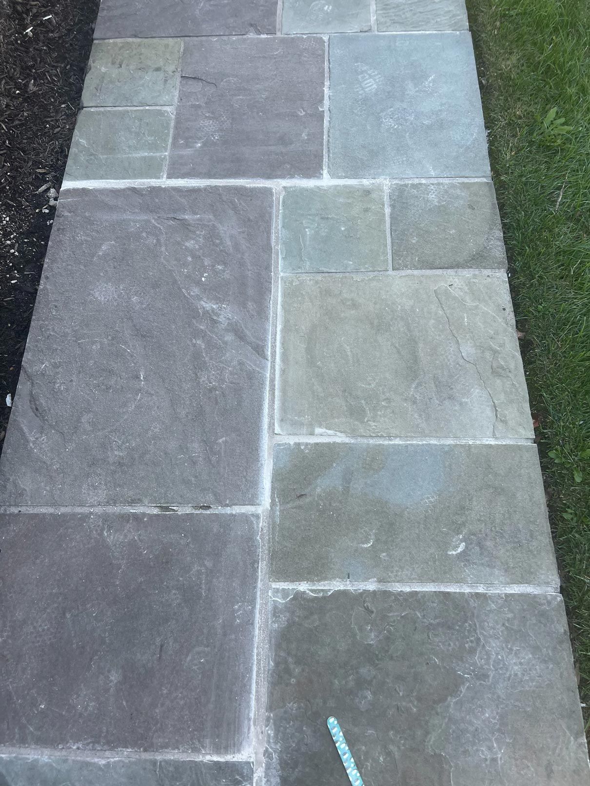 A stone walkway leading to a grassy area.