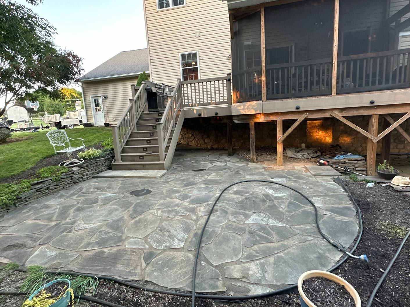 A patio with a screened in porch and stairs in front of a house.