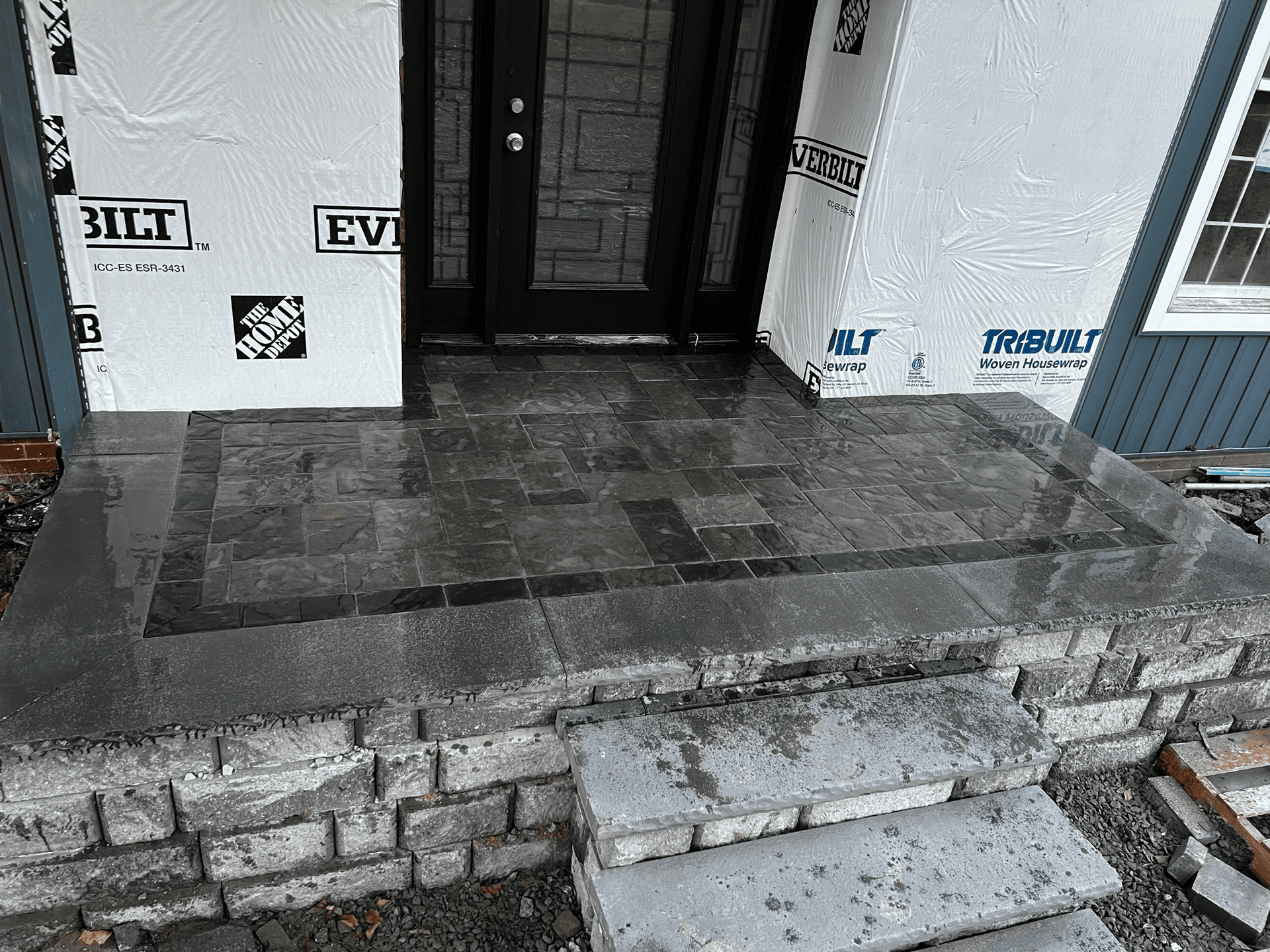 The front porch of a house is being built with bricks and steps.