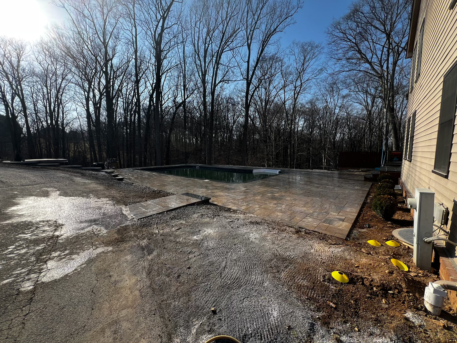 A Brick House with A Swimming Pool in The Backyard Surrounded by Trees.