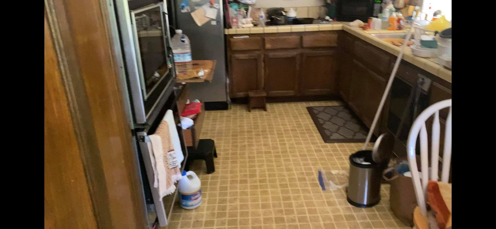 A kitchen with wooden cabinets , a refrigerator , a microwave , and a mop.