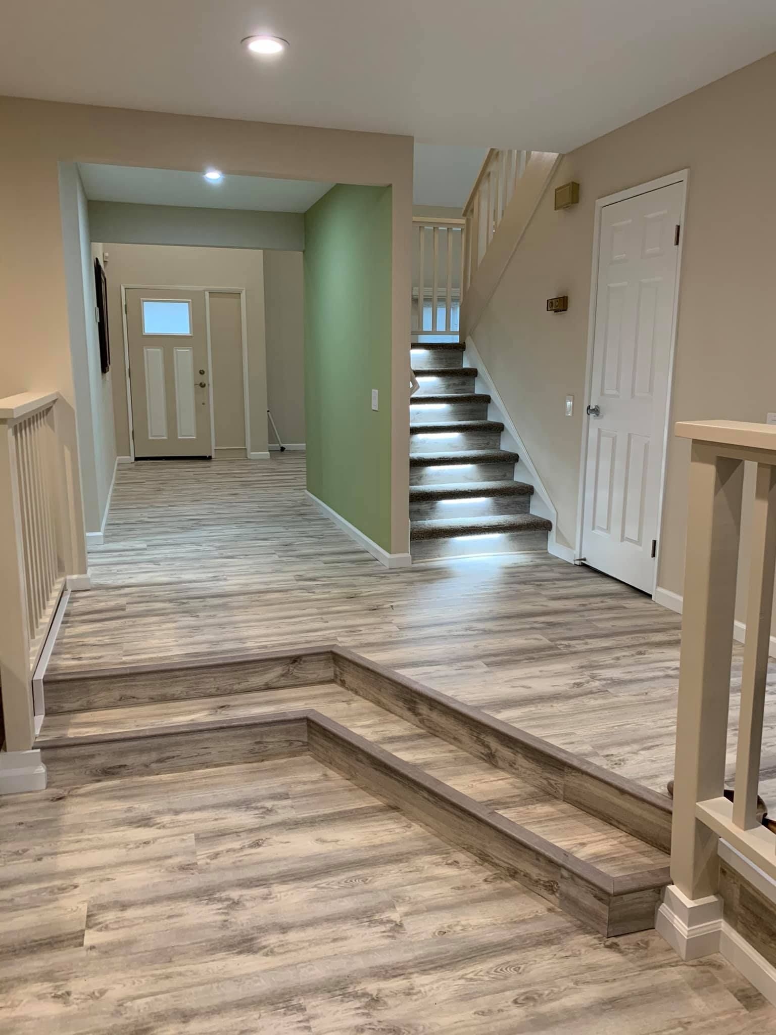 A hallway with wooden floors and stairs in a house.