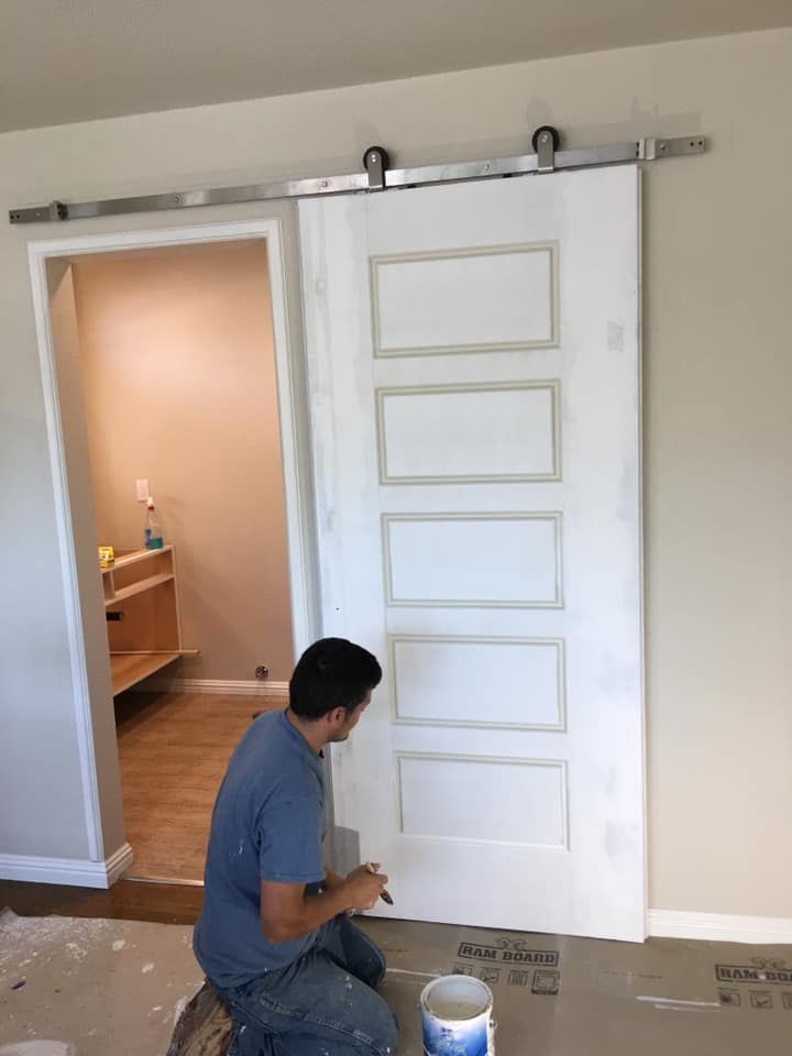 A man is painting a sliding barn door in a room.