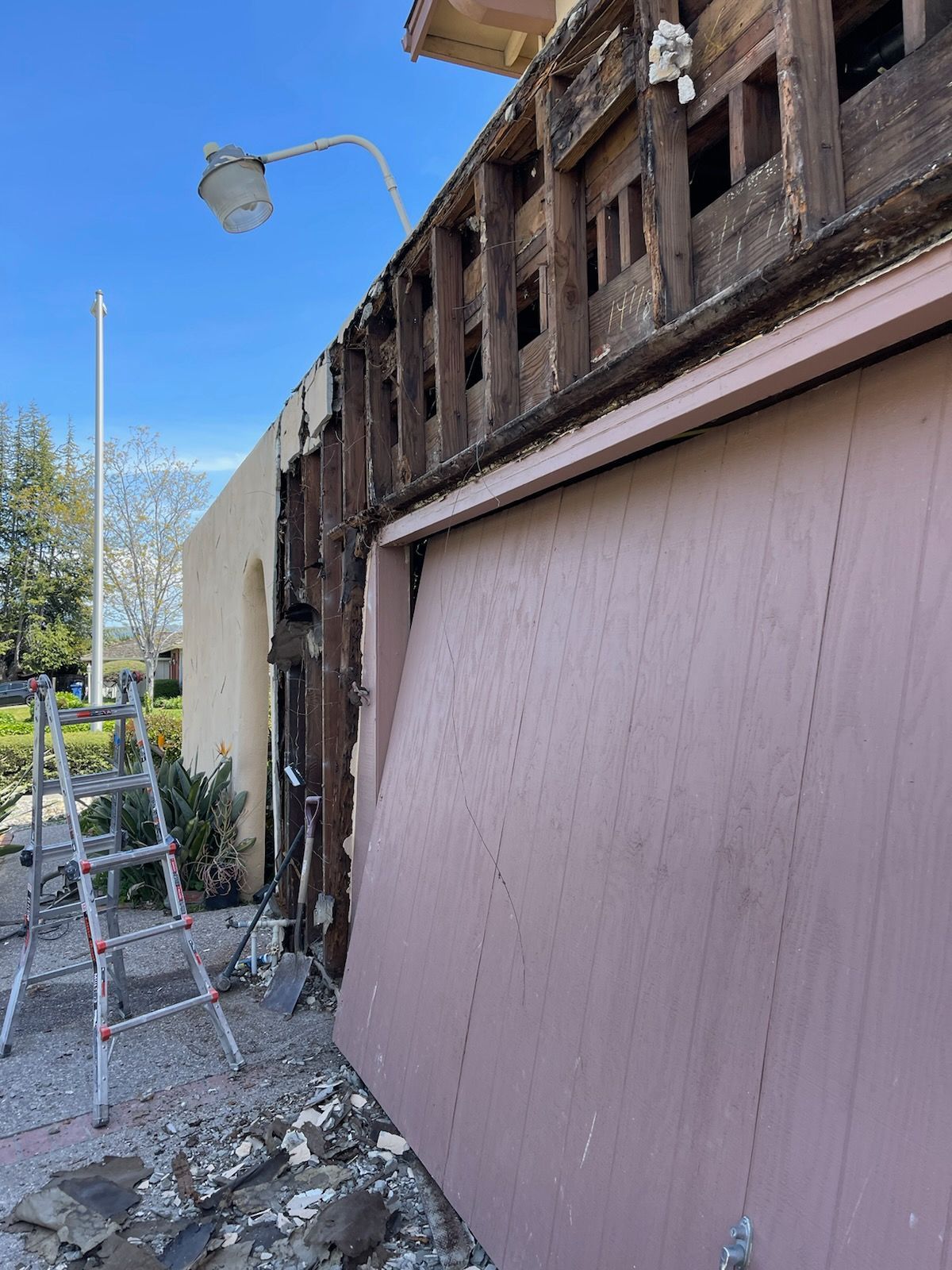 A pink garage door is being removed from a house.