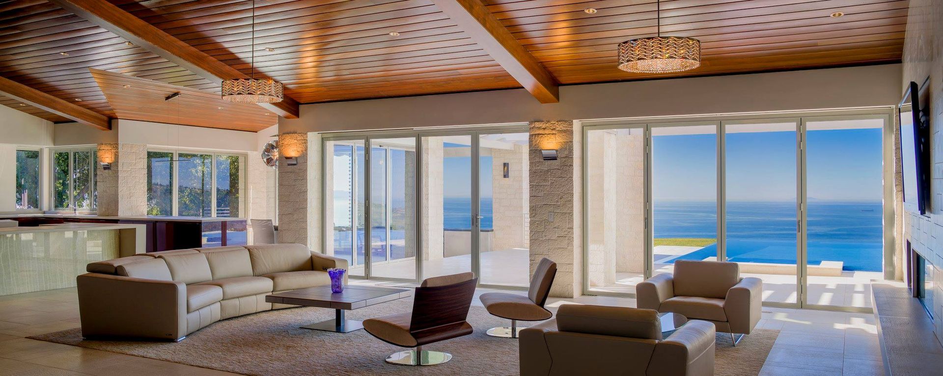 A living room with a couch , chairs , and a view of the ocean.