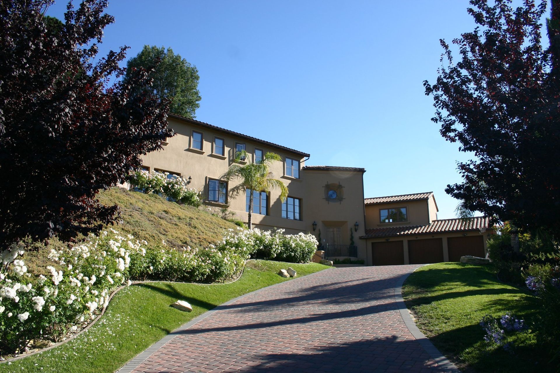 A brick driveway leading to a large house