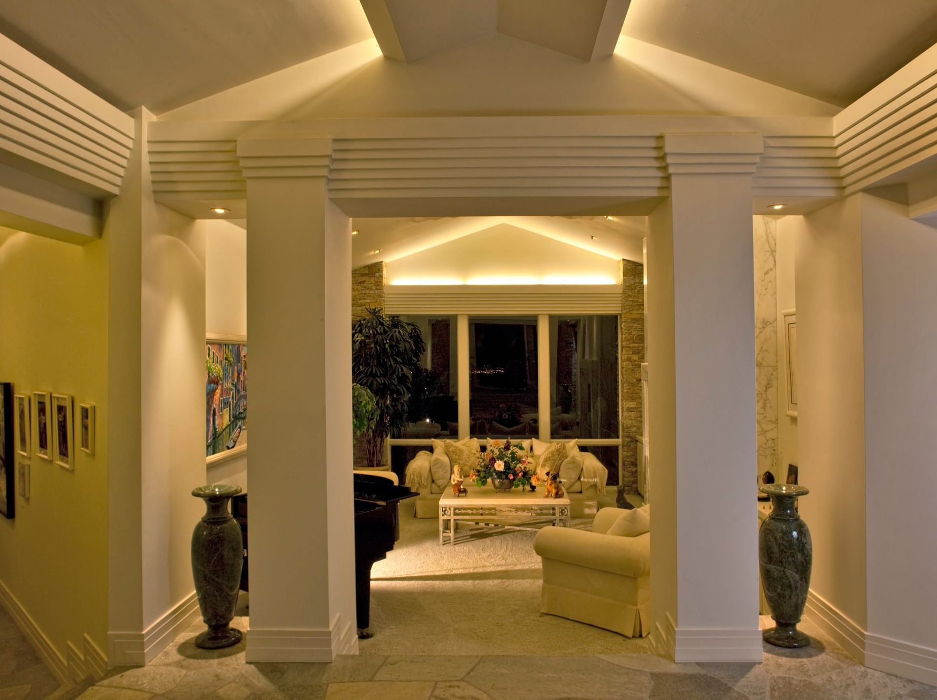 A living room with columns and a piano in it