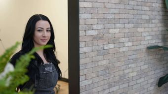 Sarah Delaney of Nirvana Permanent Makeup is standing in front of a brick wall.
