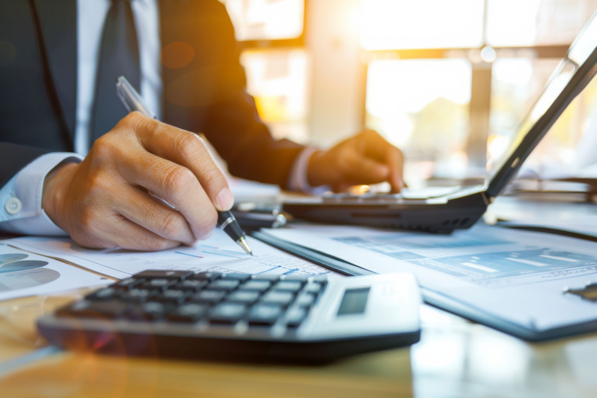 A man is sitting at a desk using a laptop and a calculator.
