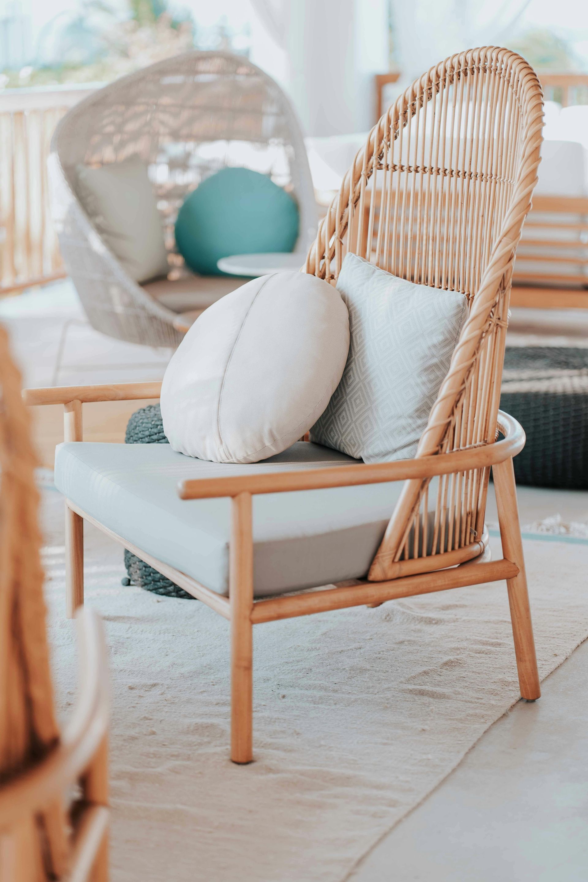 A wicker chair with two pillows on it is sitting on a rug in a room.