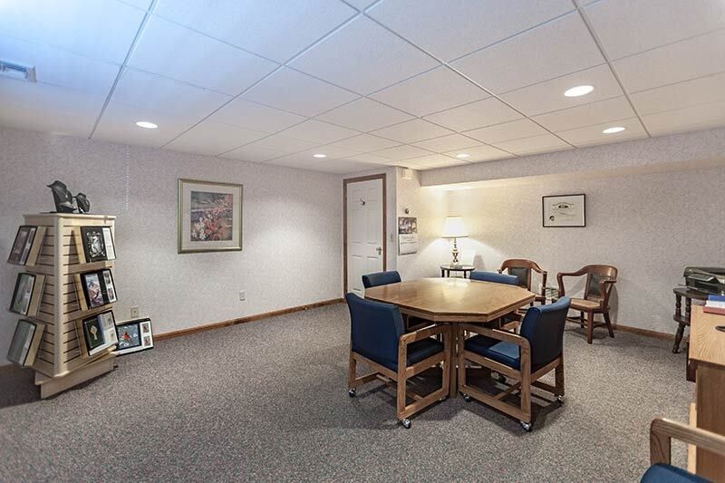 Waiting room with an octagonal table and chairs.  A photo display and framed art on the walls.