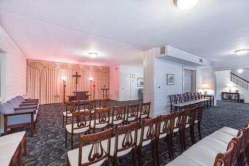 Interior of a funeral home chapel with chairs, an altar, and a stairway.