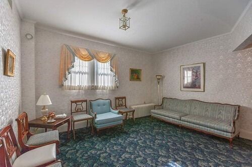 Awaiting room with floral carpet, light blue furniture, patterned wallpaper, and artwork.