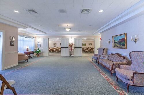 Interior of a large, formal reception area with seating, doorways, and a blue carpet.