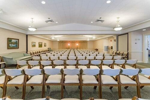 Rows of chairs face a stage in a large, bright room.