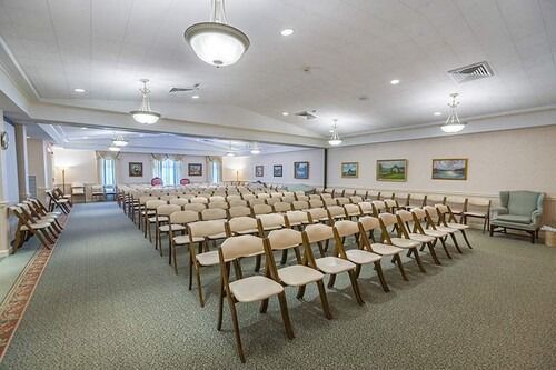Rows of chairs in a light-filled auditorium with artwork on the walls.