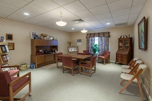 A furnished room with a table, chairs, cabinets, and decorative items.