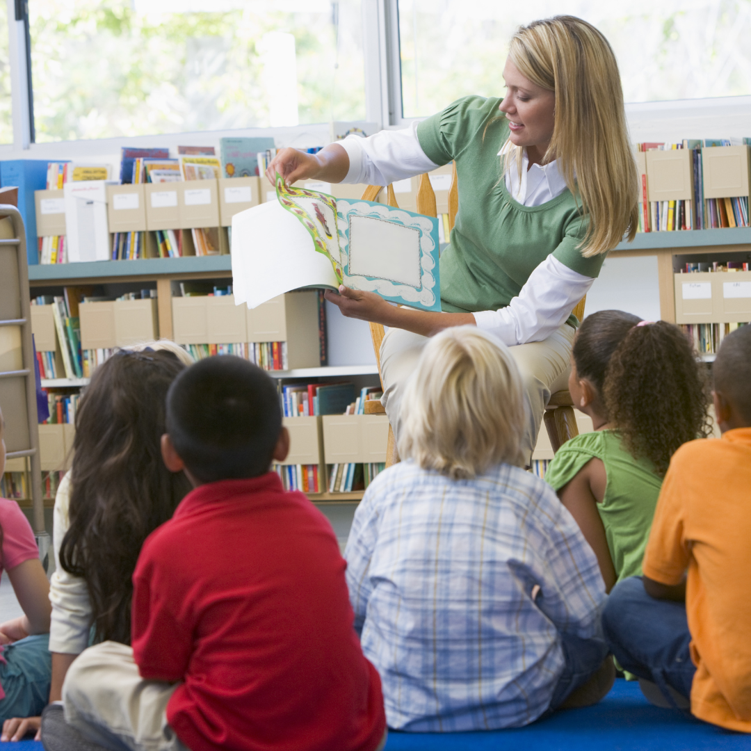 A woman is reading a book to a group of children