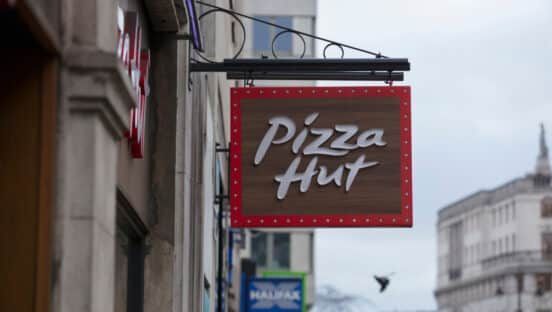 Pizza Hut sign outside building, brown and red with white text.