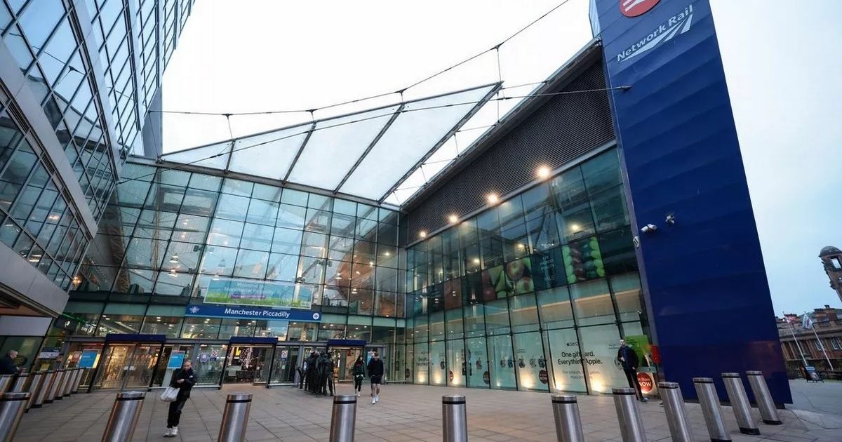 Entrance to Wembley Stadium, London. Glass facade, blue sign, people entering.