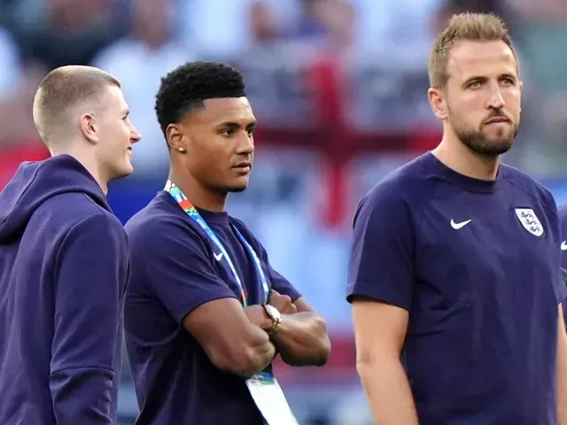 Three England soccer players in blue shirts, looking to the right.
