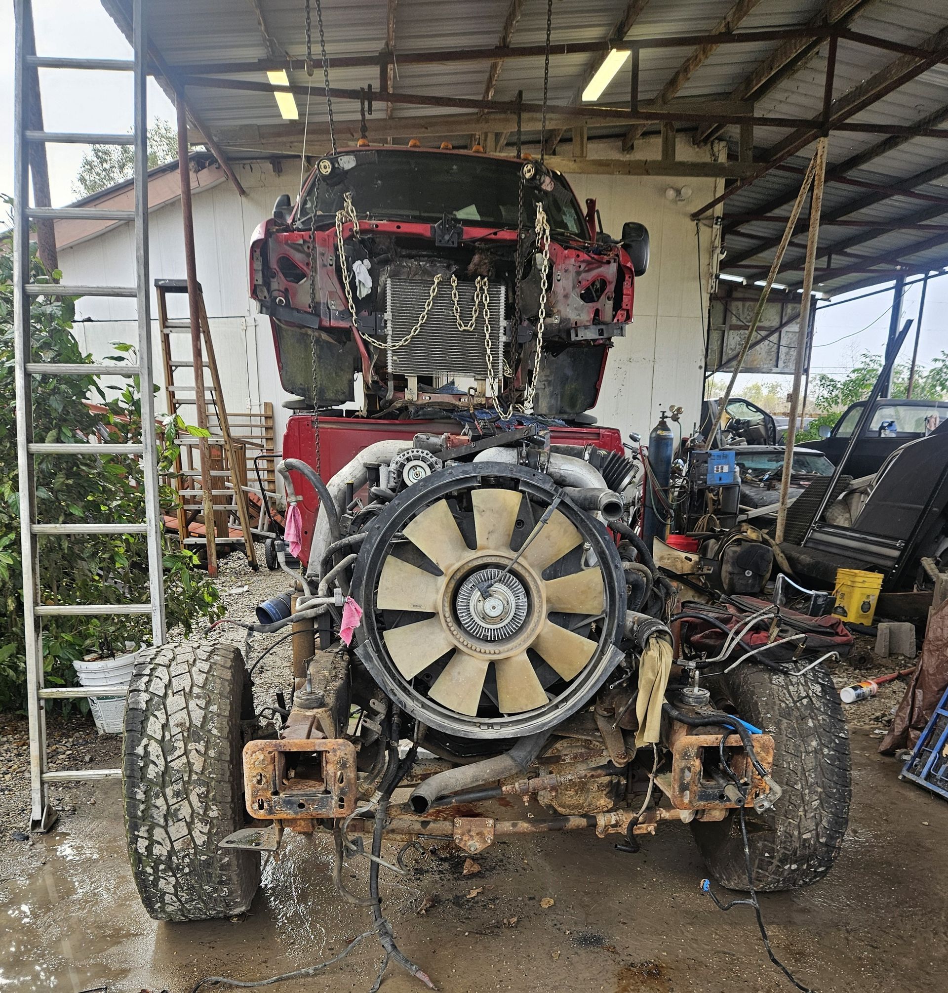 A disassembled red truck in a workshop, showing the engine, front tires, and cab framework.