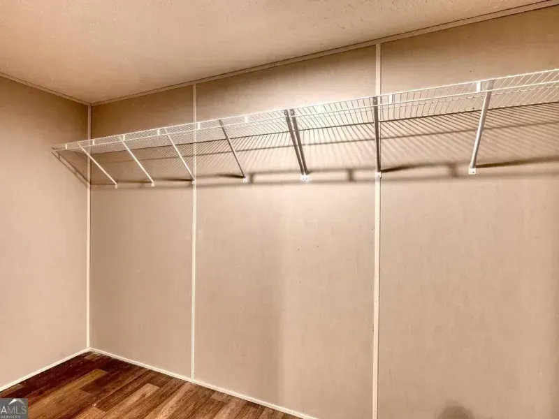 White wire shelving mounted on light-colored walls above a wood-look floor in an empty closet.