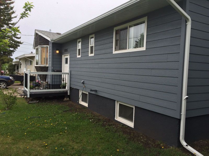A blue house with a white railing and a car parked in front of it.