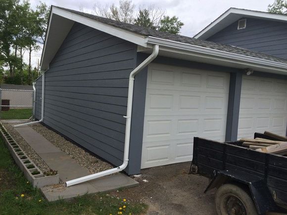 A truck is parked in front of a garage with two garage doors.