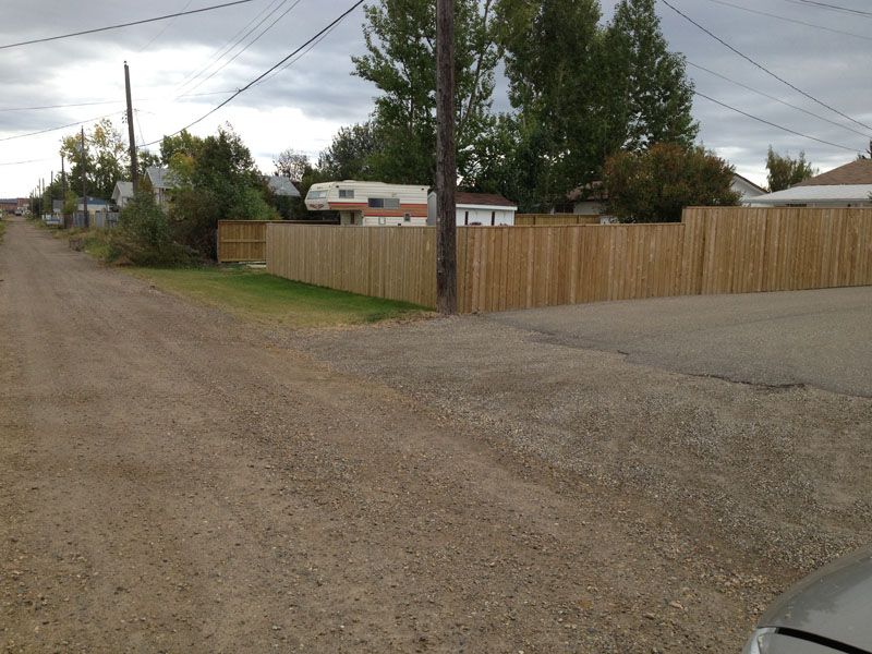 A wooden fence along the side of a dirt road
