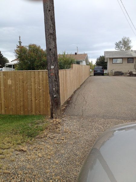 A car is parked on the side of the road next to a wooden fence