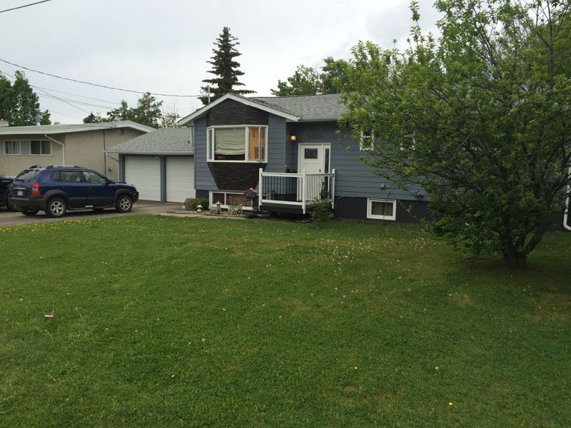 A blue car is parked in front of a house